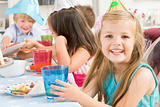 Young girl at party sitting at table with food smiling