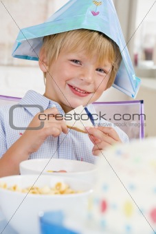 Young boy at party sitting at table with a sandwich smiling