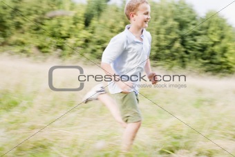 Young boy running in a field smiling