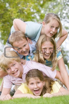 Five young friends piled on each other outdoors smiling