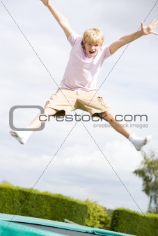 Young boy jumping on trampoline smiling