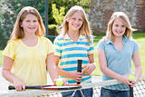 Three young girl friends with rackets on tennis court smiling