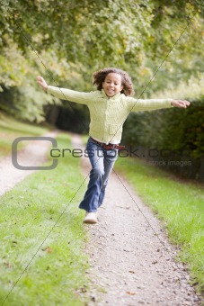 Young girl running on a path outdoors smiling