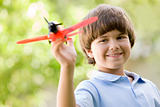 Young boy with toy airplane outdoors smiling