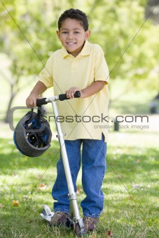Young boy outdoors on scooter smiling