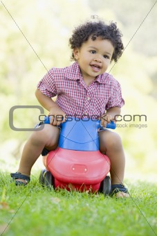 Young boy playing on toy with wheels outdoors