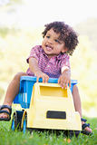 Young boy playing on toy dump truck outdoors