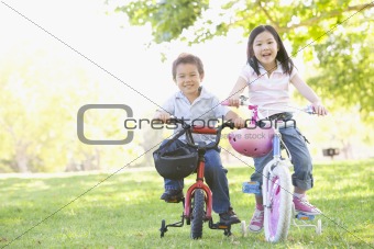 Brother and sister outdoors on bicycles smiling