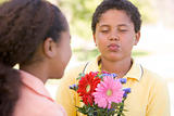 Young boy giving young girl flowers and puckering up