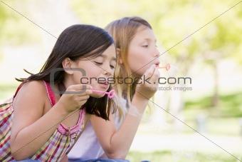 Two young girls blowing bubbles outdoors
