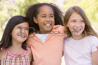 Three young girl friends outdoors smiling