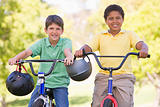 Two young boys on bicycles outdoors smiling