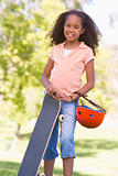 Young girl with skateboard outdoors smiling
