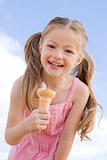 Young girl outdoors eating ice cream cone and smiling
