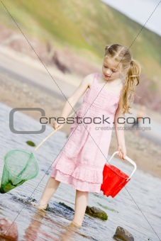 Young girl at beach with net and pail