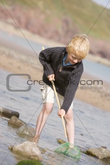 Young boy at beach with net smiling