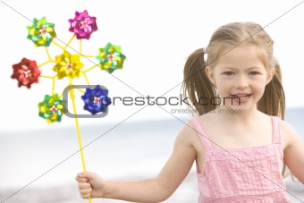 Young girl at beach with toy windmill smiling