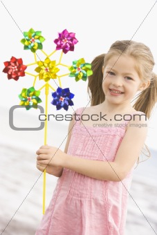 Young girl at beach with toy windmill smiling