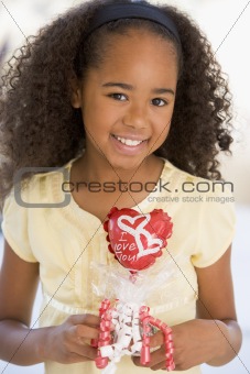 Young girl on Valentine's Day holding love themed balloon smilin