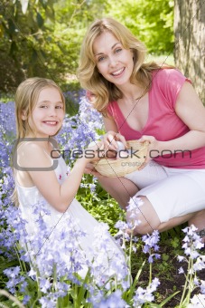 Mother and daughter on Easter looking for eggs outdoors smiling