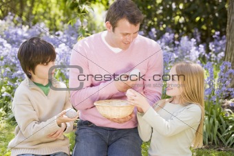Father and two young children on Easter looking for eggs outdoor