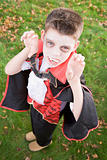 Young boy outdoors wearing vampire costume on Halloween