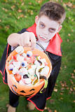 Young boy outdoors wearing vampire costume on Halloween holding 