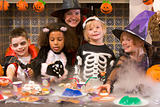Four young friends and a woman at Halloween eating treats and sm