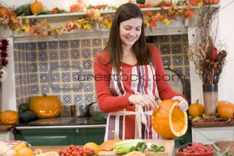 Woman carving jack o lantern on Halloween and smiling
