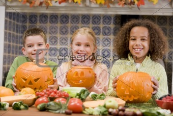 Three young friends on Halloween with jack o lanterns and food s