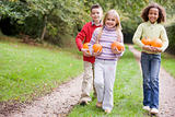 Three young friends walking on path with pumpkins smiling