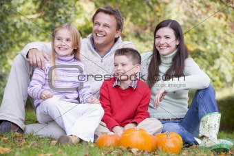 Family sitting on grass with pumpkins smiling