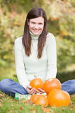 Woman sitting on grass with pumpkins smiling