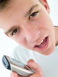 Teenage boy using cellular phone and looking mad