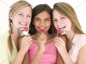 Three girl friends with suckers smiling