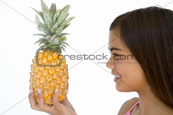 Young girl holding pineapple and smiling
