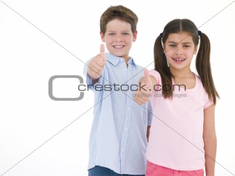 Brother and sister giving thumbs up smiling
