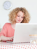 Beautiful blonde woman relaxing with her laptop while sitting in