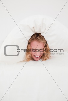 Attractive blonde female balled-up in a duvet in her bedroom