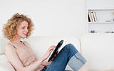Charming blonde woman relaxing with her tablet while sitting on 