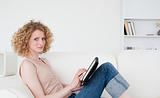 Beautiful blonde woman relaxing with her tablet while sitting on