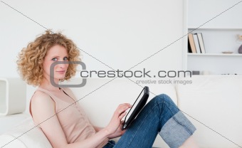 Beautiful blonde woman relaxing with her tablet while sitting on