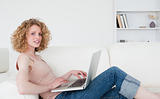 Attractive blonde woman relaxing with her laptop while sitting o