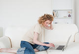 Pretty blonde woman relaxing with her laptop while sitting on a 