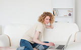 Charming blonde woman relaxing with her laptop while sitting on 