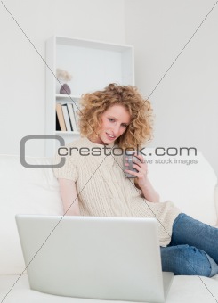 Gorgeous blonde woman relaxing with her laptop while sitting on 