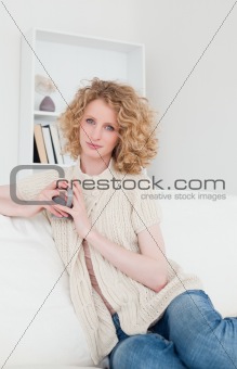 Good looking blonde female enjoying a cup of coffee while sittin