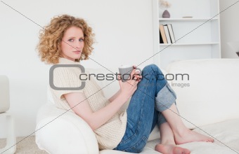 Charming blonde female enjoying a cup of coffee while sitting on