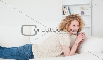 Attractive blonde woman enjoying a cup of coffee while lying on 