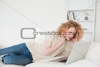 Gorgeous blonde woman relaxing with her laptop while lying on a 